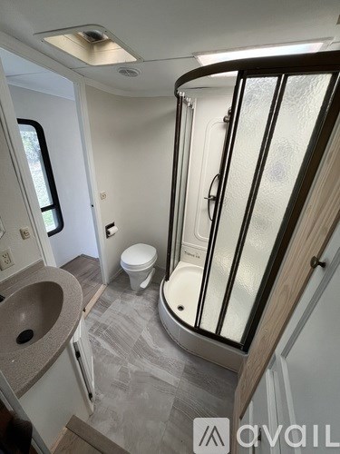 A small bathroom with a toilet, sink, and shower.