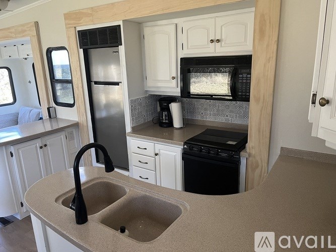 A kitchen with a sink, refrigerator, and microwave.
