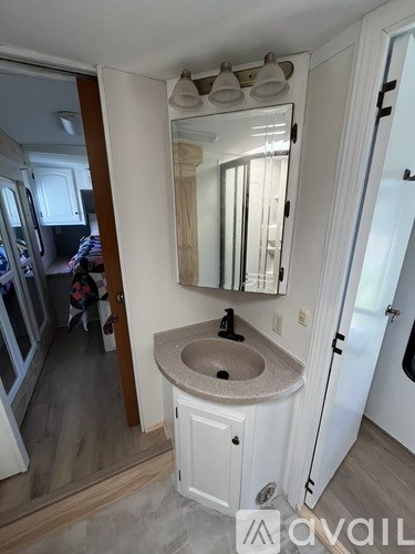 A bathroom with a sink, mirror, and a white cabinet.