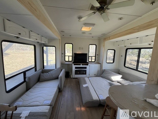 The image shows the interior of a camper with a bed, a table, and a TV.