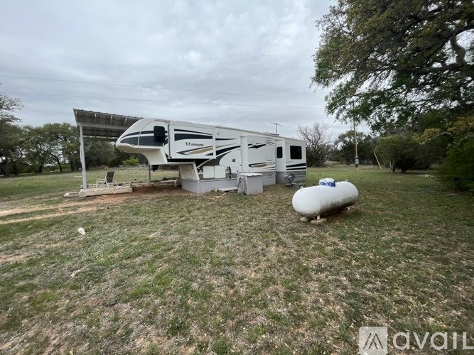 A solar-powered house with a trailer and a tank in the yard.
