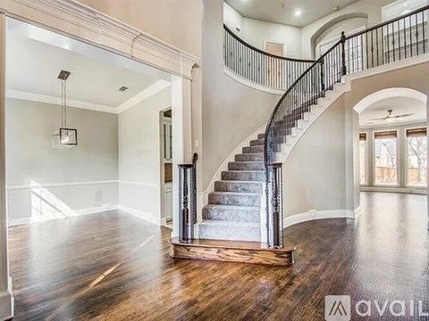 A spacious home interior with a curved staircase and hardwood floors.