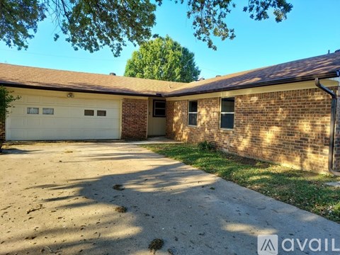 A two-car garage with a brick wall and a tree in the background.