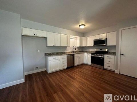 A kitchen with white cabinets and a wooden floor.