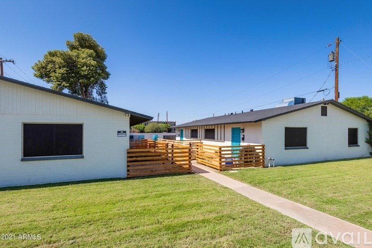 A white house with a blue door and a wooden fence in front.