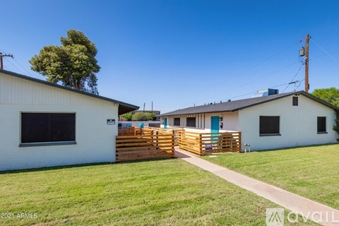 A white house with a blue door and a wooden fence in front.