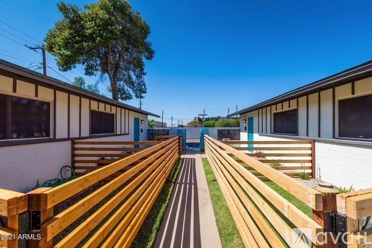 A long wooden bench is in the foreground of a sunny day.