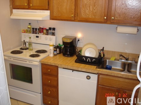 A kitchen with a white oven, white dishwasher, and wooden cabinets.