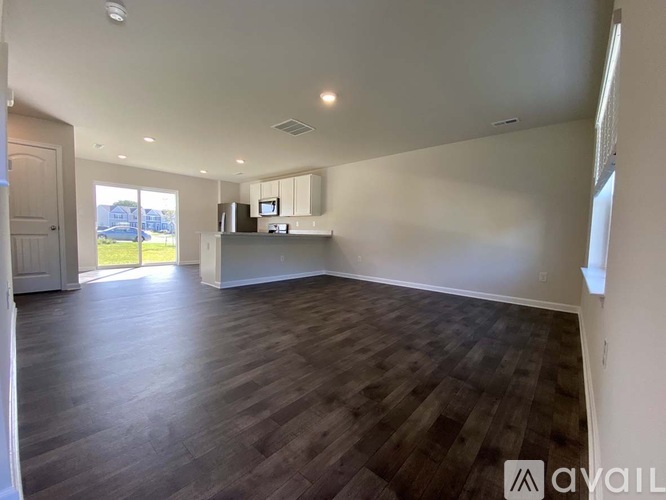 A spacious room with wooden flooring and white walls.