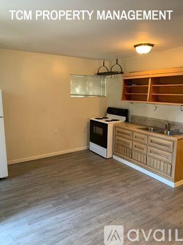 A kitchen area with wooden flooring and a white wall.