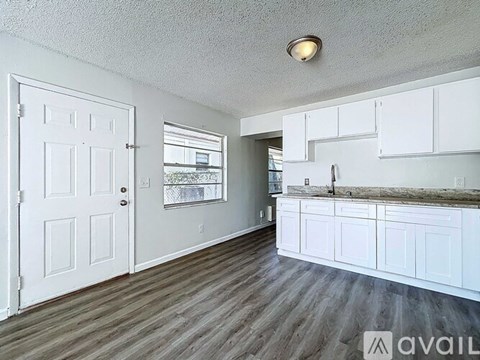 A kitchen with white cabinets and a wooden floor.