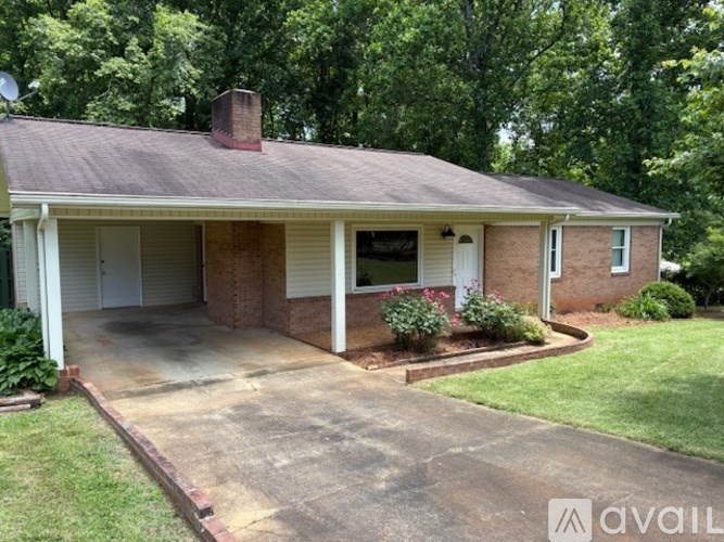 A house with a brown roof and a white door is surrounded by greenery.