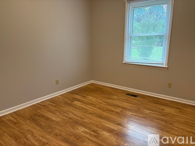 A room with a window and wooden flooring.