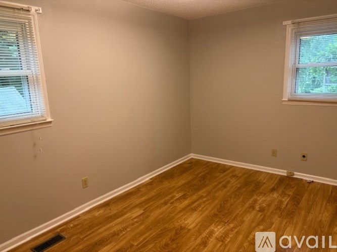 A room with wooden flooring and a window with blinds.