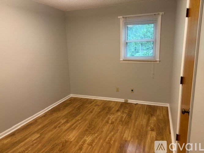 A room with wooden flooring and a window.