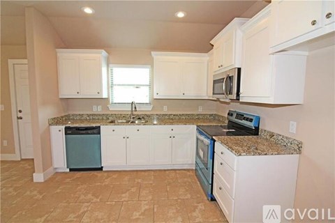 A kitchen with white cabinets and a granite countertop.