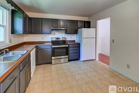 A kitchen with a white refrigerator and black cabinets.