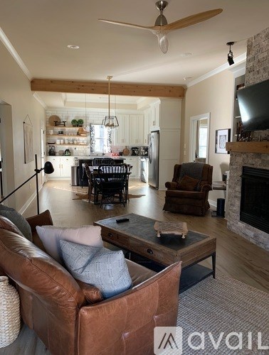 A living room with a brown leather couch and a fireplace.