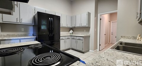 A kitchen with a black stove top and a black fridge.
