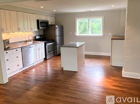 A kitchen with wooden floors and white cabinets.