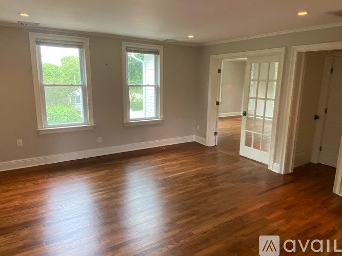 A room with wooden floors and two windows.