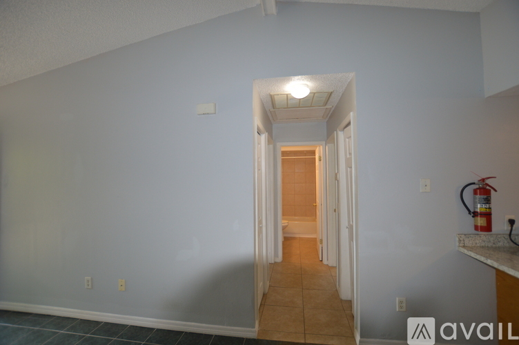 A hallway with a door at the end and a fire extinguisher on the wall.