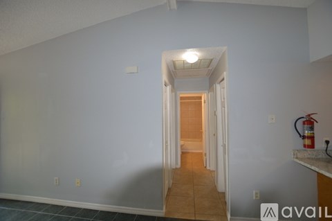 A hallway with a door at the end and a fire extinguisher on the wall.