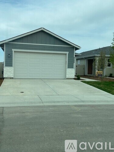 A house with a garage door that is closed and a sign that says sold.