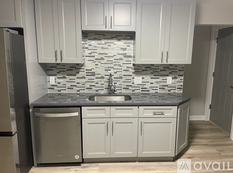 A kitchen with white cabinets and a grey backsplash.
