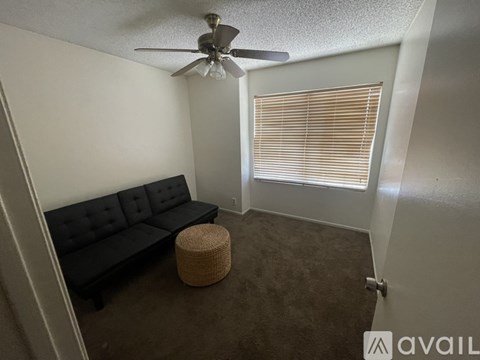 A living room with a black couch and a ceiling fan.