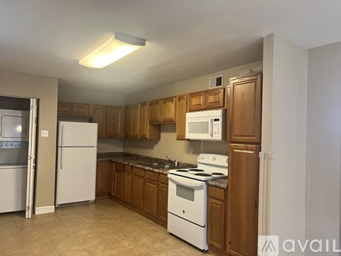 A kitchen with white appliances and wooden cabinets.