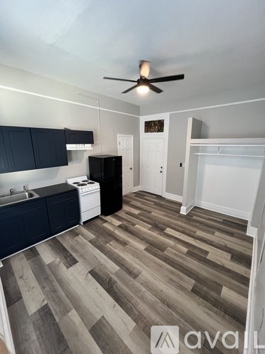 A kitchen with dark blue cabinets and a wooden floor.