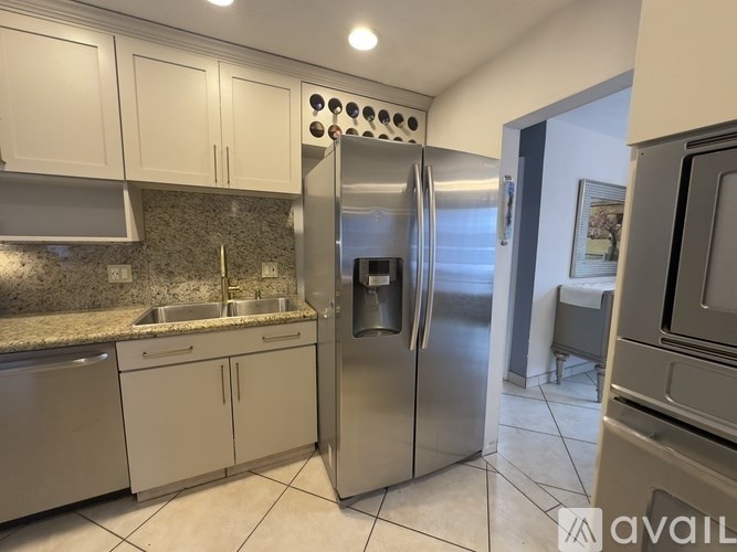 A kitchen with a stainless steel refrigerator and white cabinets.