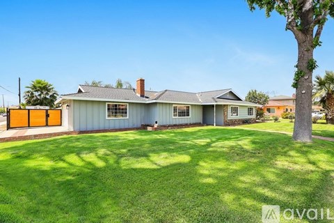 A house with a green lawn and a tree in front.