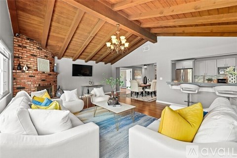 A living room with white couches and a wooden ceiling.