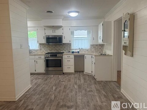 A kitchen with white cabinets and a grey floor.