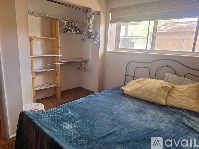 A bedroom with a blue bedspread and a wooden wardrobe.