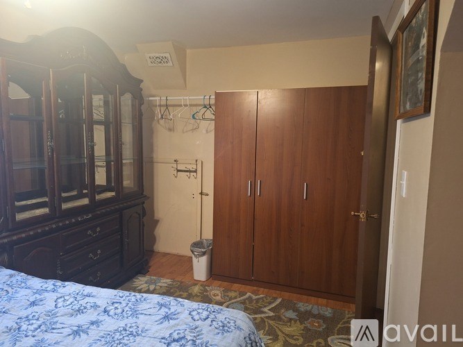 A bedroom with a bed, wardrobe, and a trash can.