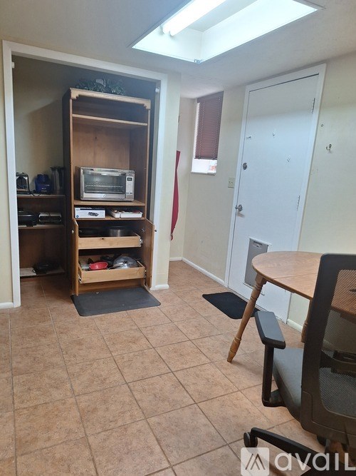 A room with a desk, chair, and a pantry with a microwave and oven.