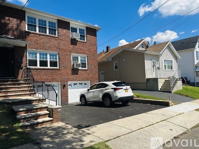 A white car is parked in front of a brick house.