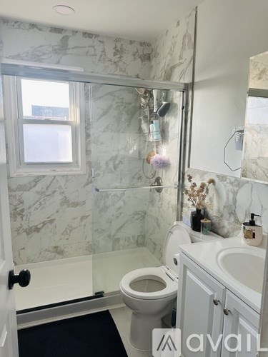 A bathroom with marble walls and a glass shower stall.