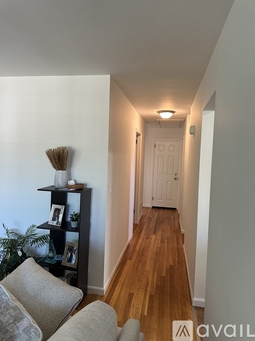 A hallway with a wooden floor and a white door.