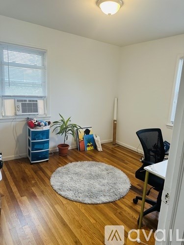 A room with a white rug on the floor and a black chair.