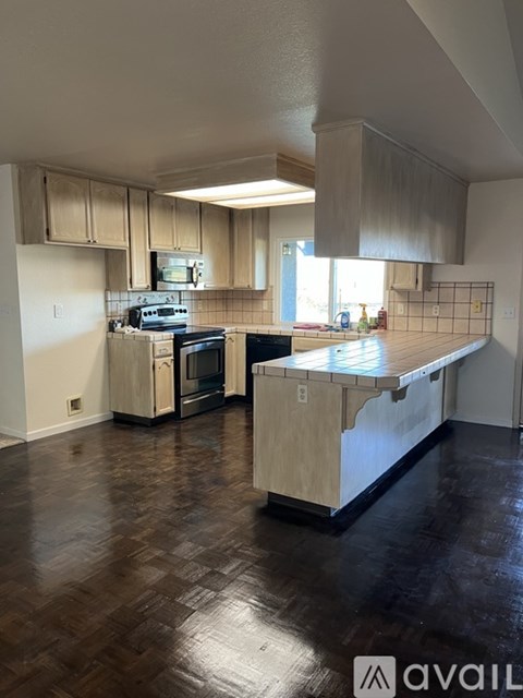 A kitchen with wooden cabinets and a black floor.