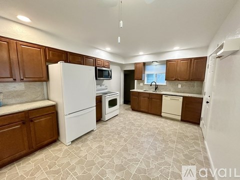 A kitchen with white appliances and brown cabinets.