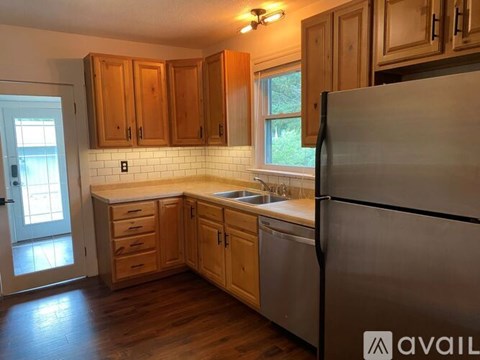 A kitchen with wooden cabinets and a stainless steel refrigerator.