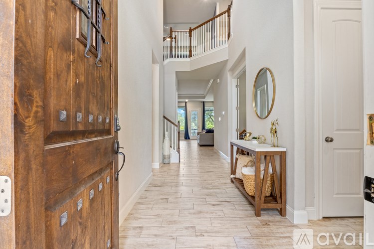 A hallway with a wooden door and a mirror on the wall.