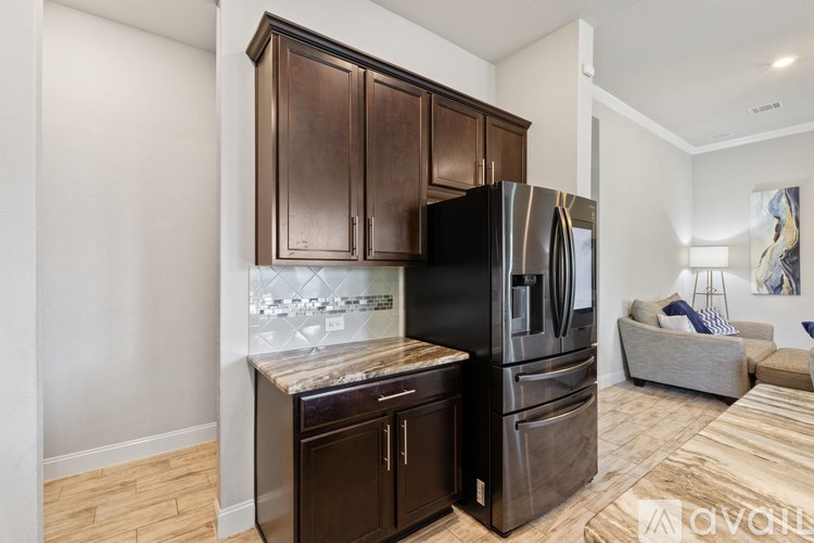 A kitchen with dark wood cabinets and a black refrigerator.