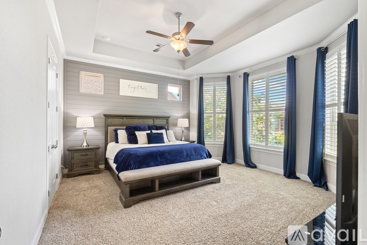 A bedroom with a bed, nightstand, and ceiling fan.