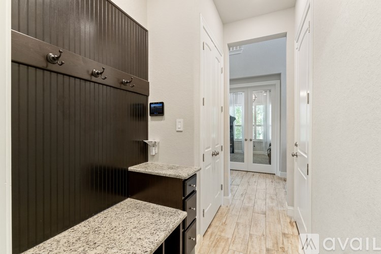 A hallway with a bench, a door, and a wall-mounted TV.